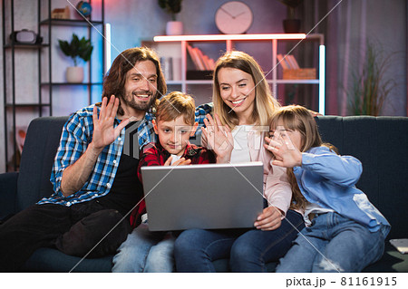 Family smiling and waving during video chat on laptop 81161915