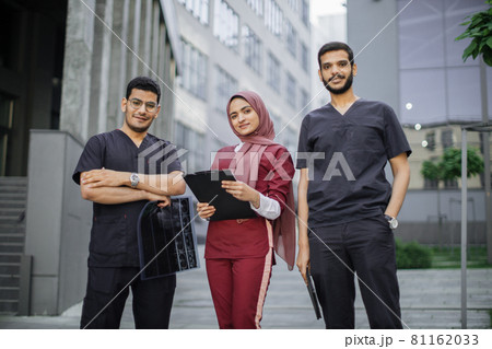 Three doctors, Muslim lady in hijab and two Arabian men, working in front of the clinic 81162033