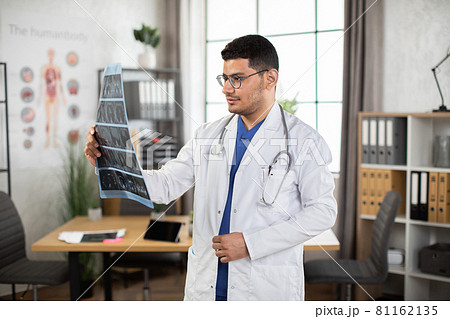 Male Arab doctor oncologist physician examining lungs x-ray computerized tomography scan 81162135
