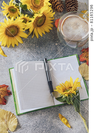 Good Morning. To do list concept. A bouquet of large sunflowers, coffee cup and empty notebook on a stone table. 81165296
