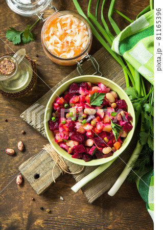Beetroot salad vinaigrette with sauerkraut, pickled cucumber and vegetables on a wooden rustic table. Top view flat lay background. 81165396