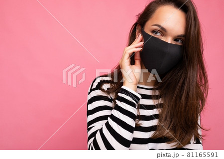 Young beautiful woman in reusable virus protective mask on face against coronavirus isolated on the 81165591