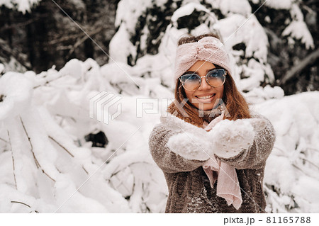 A girl in a sweater and glasses in winter in a snow-covered forest 81165788