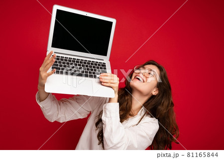 Close-up portrait of overjoyed Beautiful smiling happy young woman holding computer laptop looking Close-up portrait of overjoyed Beautiful smiling happy young woman holding computer laptop looking 81165844