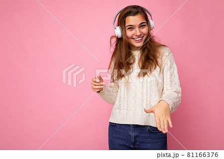 Beautiful happy smiling young brunette curly woman wearing white sweater isolated on pink background Beautiful happy smiling young brunette curly woman wearing white sweater isolated on pink background 81166376