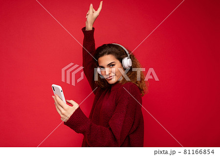 Shot of beautiful young brunette curly woman wearing dark red sweater isolated over red background Shot of beautiful young brunette curly woman wearing dark red sweater isolated over red background 81166854
