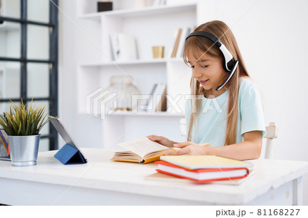 Little caucasian girl in headphones have video call distant class with teacher at home 81168227