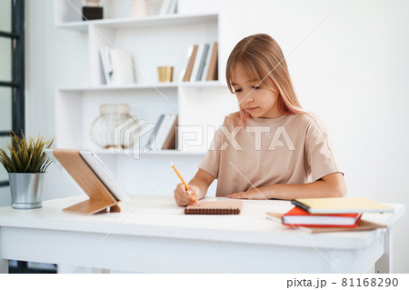Teenage girl making notes in notepad, doing homework at table at home Teenage girl making notes in notepad, doing homework at table at home 81168290