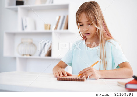 Teenage girl making notes in notepad, doing homework at table at home Teenage girl making notes in notepad, doing homework at table at home 81168291
