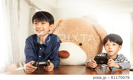 クマと並んでゲームを楽しむ男の子 81170076