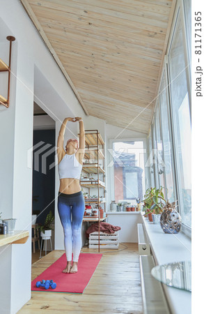 Beautiful woman with bare tummy does sports exersices standing on balcony Beautiful woman with bare tummy does sports exersices standing on balcony 81171365