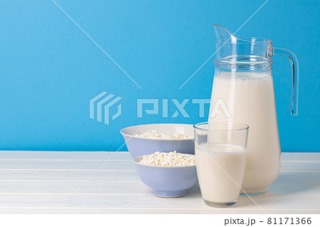 Glass pitcher of milk and bowl of cottage cheese on wooden table 81171366