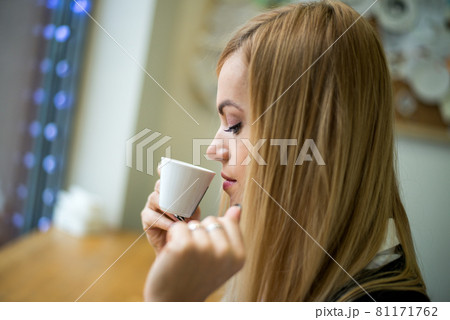 Beautiful blonde girl drinks coffee in a cafe 81171762