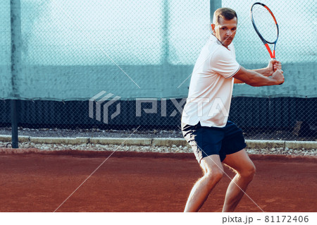 Young man plays tennis outdoors on tennis court in the morning Young man plays tennis outdoors on tennis court in the morning 81172406