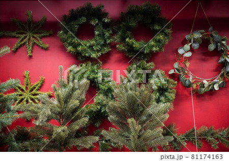 Selection of Christmas wreaths on a red wall in a store. 81174163