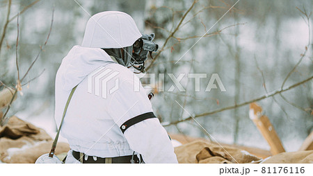 German Wehrmacht Infantry Soldier In World War II Soldiers Sitting In Ambush In Winter Forest And Looking At Old Army Binoculars. Historical Re-enactment. WWII. Winter Snowy Day German Wehrmacht Infantry Soldier In World War II Soldiers Sitting In Ambush In Winter Forest And Looking At Old Army Binoculars. Historical Re-enactment. WWII. Winter Snowy Day 81176116