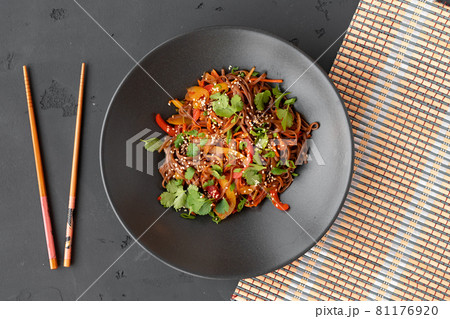 Top view of wok noodles with vegetables and meat in bowl on gray background Top view of wok noodles with vegetables and meat in bowl on gray background 81176920