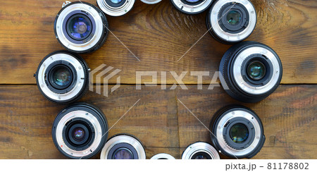 Several photographic lenses lie on a brown wooden background. Space for text Several photographic lenses lie on a brown wooden background. Space for text 81178802