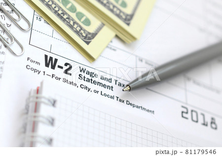 The pen, notebook and dollar bills is lies on the tax form W-2 Wage and Tax Statement. The time to pay taxes 81179546