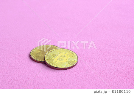 Two golden bitcoins lies on a blanket made of soft and fluffy light pink fleece fabric. Physical visualization of virtual crypto currency 81180110