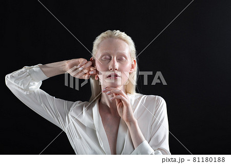 Young blonde albino woman doing face building facial gymnastics self massage and rejuvenating exercises on black background Young blonde albino woman doing face building facial gymnastics self massage and rejuvenating exercises on black background 81180188