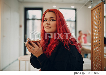 European plus size woman. Young red pink haired body positive girl sitting in cafe with coffee drink. 81180288