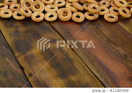 A lot of fresh yellow bagels lie on the surface of the old dark wood. A popular kind of flour products. One of the traditional Russian treats for tea A lot of fresh yellow bagels lie on the surface of the old dark wood. A popular kind of flour products. One of the traditional Russian treats for tea 81180569