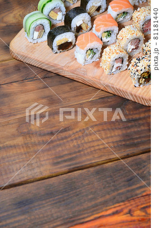 Sushi set of a number of rolls is located on a wooden cutting board on a table in the kitchen of a sushi bar. A traditional dish of oriental cuisine Sushi set of a number of rolls is located on a wooden cutting board on a table in the kitchen of a sushi bar. A traditional dish of oriental cuisine 81181440