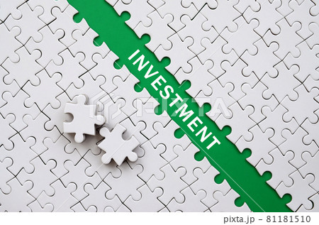 Investment. The green path is laid on the platform of a white folded jigsaw puzzle. The missing elements of the puzzle are stacked nearby Investment. The green path is laid on the platform of a white folded jigsaw puzzle. The missing elements of the puzzle are stacked nearby 81181510