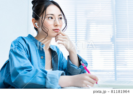 イヤホンをして勉強する眼鏡の若い女性 イヤホンをして勉強する眼鏡の若い女性 81181964