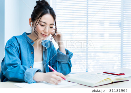イヤホンをして勉強する眼鏡の若い女性 81181965