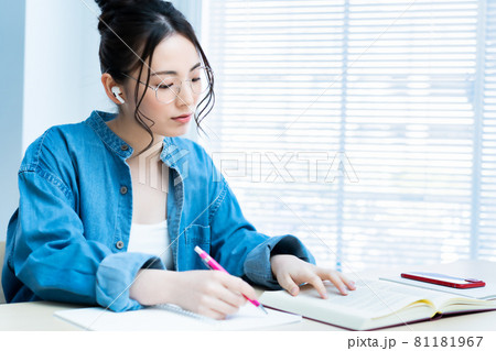 イヤホンをして勉強する眼鏡の若い女性 81181967