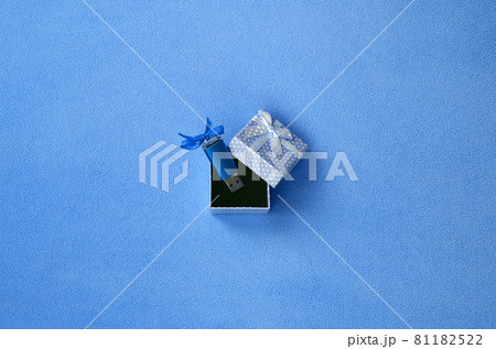 Brilliant blue usb flash memory card with a blue bow lies in a small gift box in blue with a small bow on a blanket of soft and furry light blue fleece fabric. Classic female gift memory card design 81182522