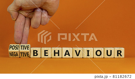 Positive or negative behaviour symbol. Businessman turns cubes, changes words negative behaviour to positive behaviour. Orange background, copy space. Business, positive or negative behaviour concept. 81182672