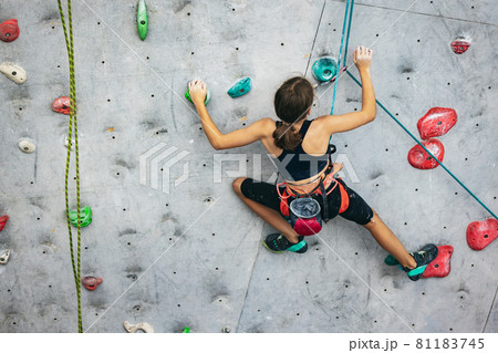 One cute teen girl practicing on the rock wall in climbing center. Concept of sportive lifestyle, activity, happy childhood One cute teen girl practicing on the rock wall in climbing center. Concept of sportive lifestyle, activity, happy childhood 81183745