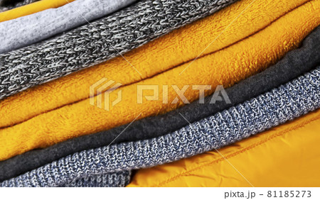 Pile of the grey and yellow warm knitted sweaters and jumpers close up 81185273