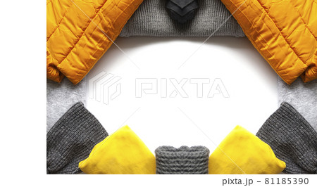 Warm winter wear on white background. Copy space. Yellow and grey trendy fashion colors. Knitted jumpers, jackets, mittens and plaids. Warm winter wear on white background. Copy space. Yellow and grey trendy fashion colors. Knitted jumpers, jackets, mittens and plaids. 81185390