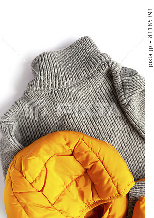 Warm yellow jacket and woolen knitted jumper on white background. Fashion outfit. Bright trendy colors. Home storage. Small space organizing. Warm yellow jacket and woolen knitted jumper on white background. Fashion outfit. Bright trendy colors. Home storage. Small space organizing. 81185391
