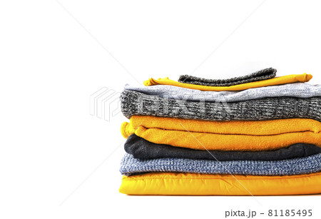 Pile of the warm knitted clothes. Warm yellow and grey sweaters and jumpers in stack on white background. Pile of the warm knitted clothes. Warm yellow and grey sweaters and jumpers in stack on white background. 81185495