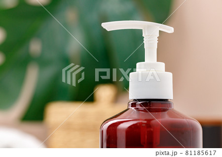 Brown transparent skincare product bottle with dispenser on a light background 81185617