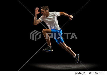 One muscular, sportive man, male athlete, runner training isolated on dark studio background with spotlight. Concept of action, motion, youth, healthy lifestyle. 81187888