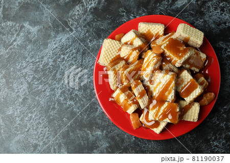 Plate with wafers with caramel on black smokey table Plate with wafers with caramel on black smokey table 81190037