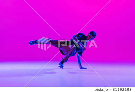 Young stylish man, hip-hop dancer dancing solo in modern clothes isolated over bright magenta background at dance hall in neon light. Young stylish man, hip-hop dancer dancing solo in modern clothes isolated over bright magenta background at dance hall in neon light. 81192193