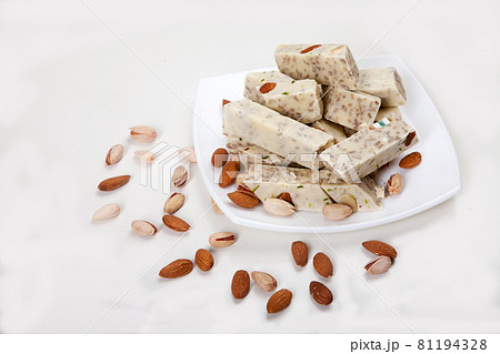 Halva made from sunflower seeds, almonds and pistachios lies on a plate on a white background. Copy spaes. Halva made from sunflower seeds, almonds and pistachios lies on a plate on a white background. Copy spaes. 81194328