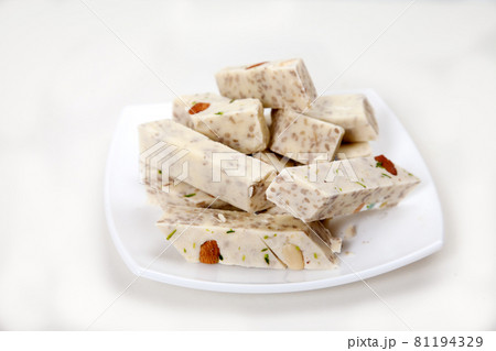 Halva with pistachios and almonds is on a white porcelain plate on a white background. Halva with pistachios and almonds is on a white porcelain plate on a white background. 81194329