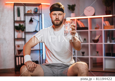 Middle aged man sitting on fitball and holding water bottle Middle aged man sitting on fitball and holding water bottle 81194422