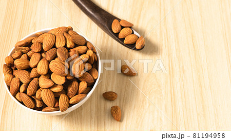 Almond nuts in a white bowl on wooden background, top view, flat lay, top-down, selective focus.copy space. 81194958