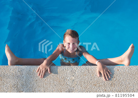 The girl sits on a twine in the pool. The child plays with and laughs. Beautiful summer picture. Bright blue water in the pool. The concept of summer, relaxation and recuperation 81195504