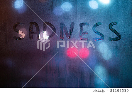 the word sadness written by finger on night wet glass with blurred blue and red lights in background the word sadness written by finger on night wet glass with blurred blue and red lights in background 81195559