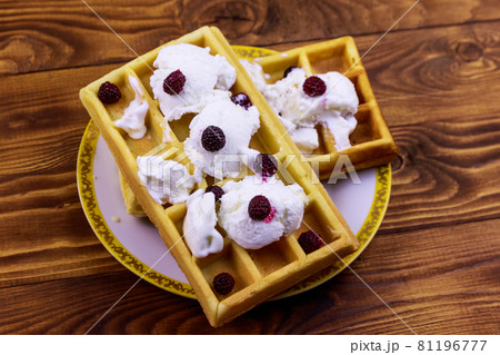 Belgian waffles with ice cream and blackberries on wooden table Belgian waffles with ice cream and blackberries on wooden table 81196777